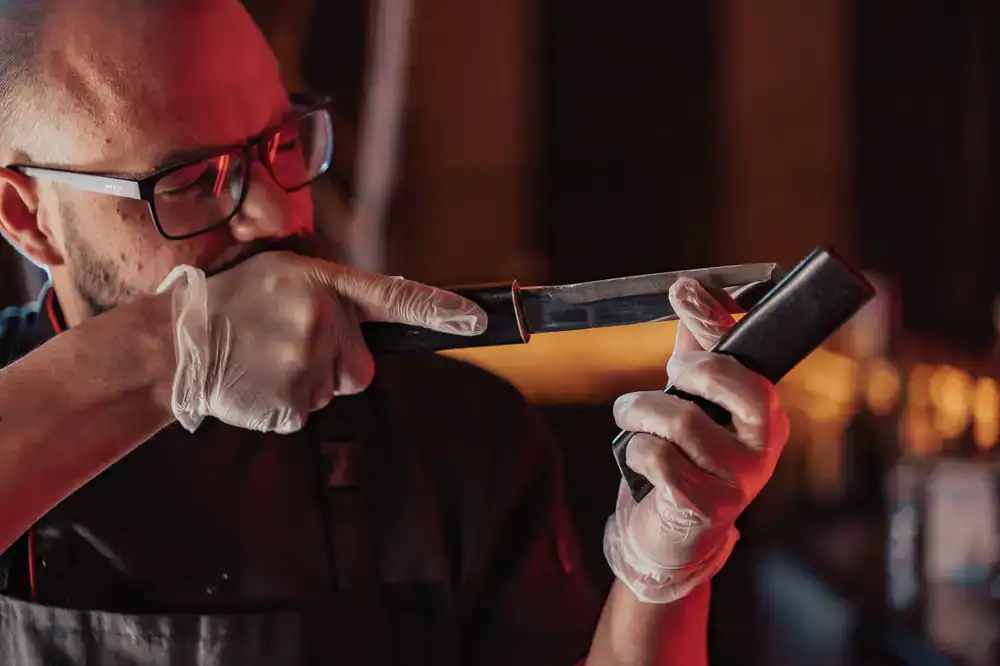 Close up of a professional chef carefully drying a premium kitchen knife blade with a microfiber cloth
