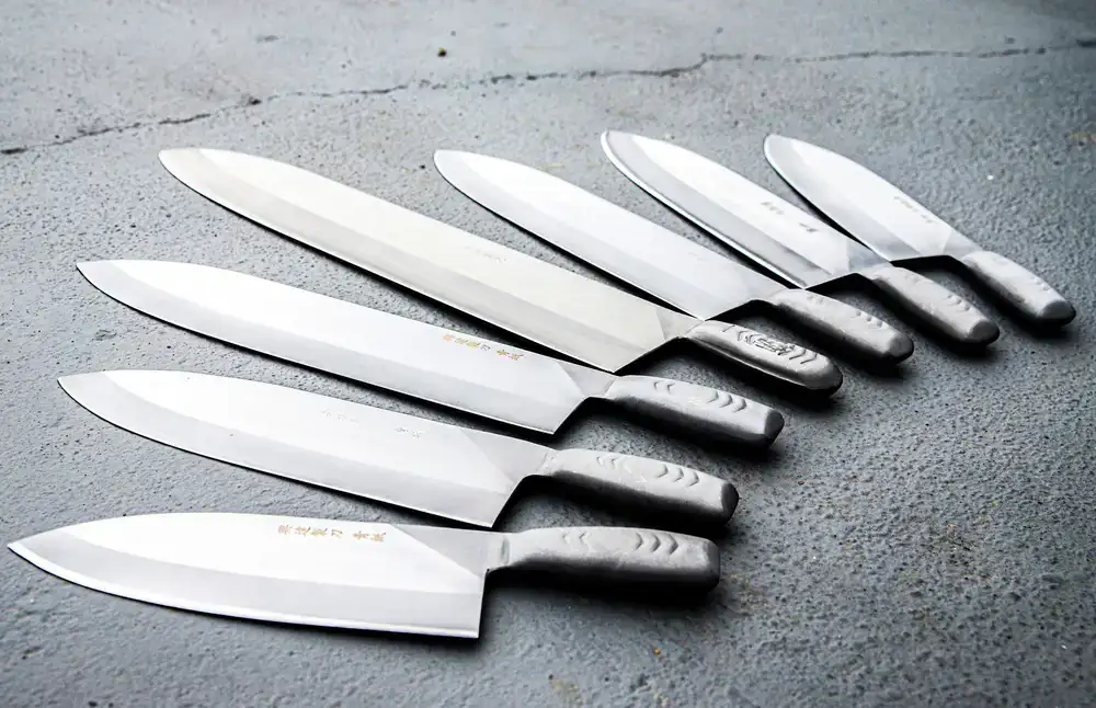 Collection of premium chef knives laid out cleanly on a dark textured surface